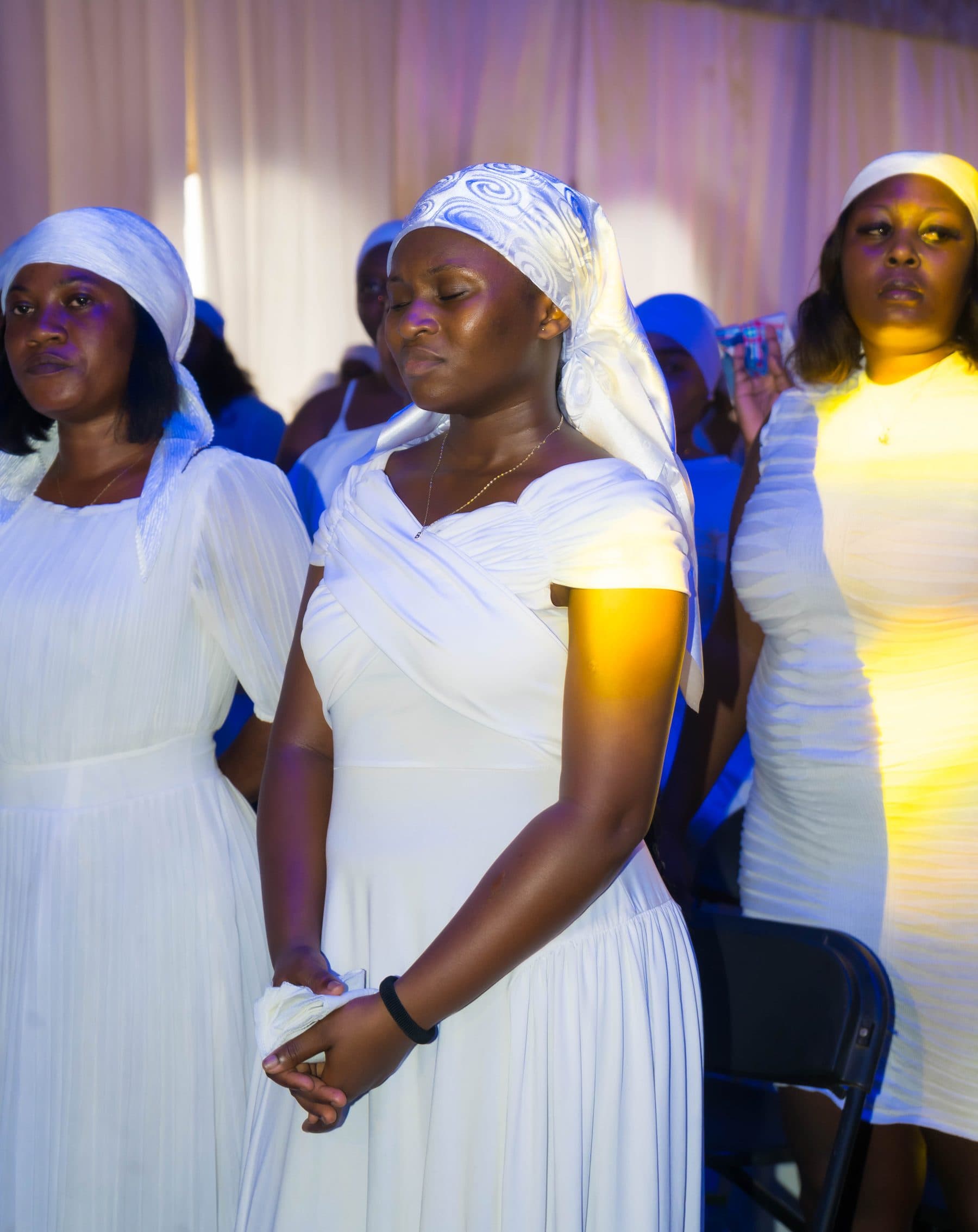 A member in quiet worship, hands clasped, at a White Outreach Movement service